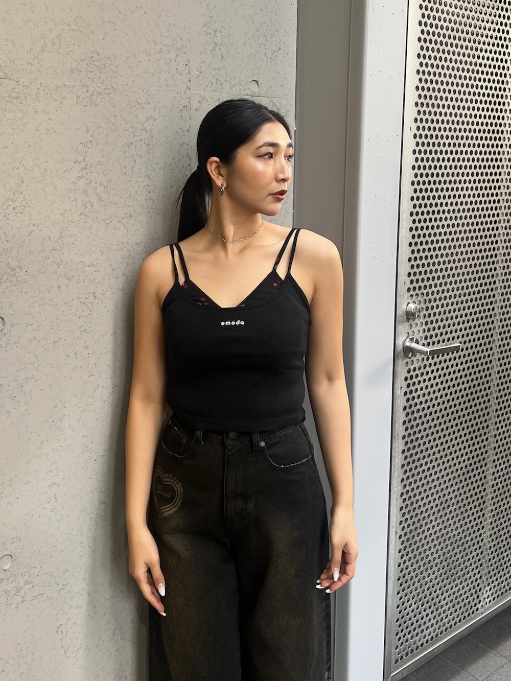 ブラック系のキャミソール、ブラック系のデニムパンツ、ブラウン系のスニーカーを着用したレディースの春コーディネートの4枚目の写真