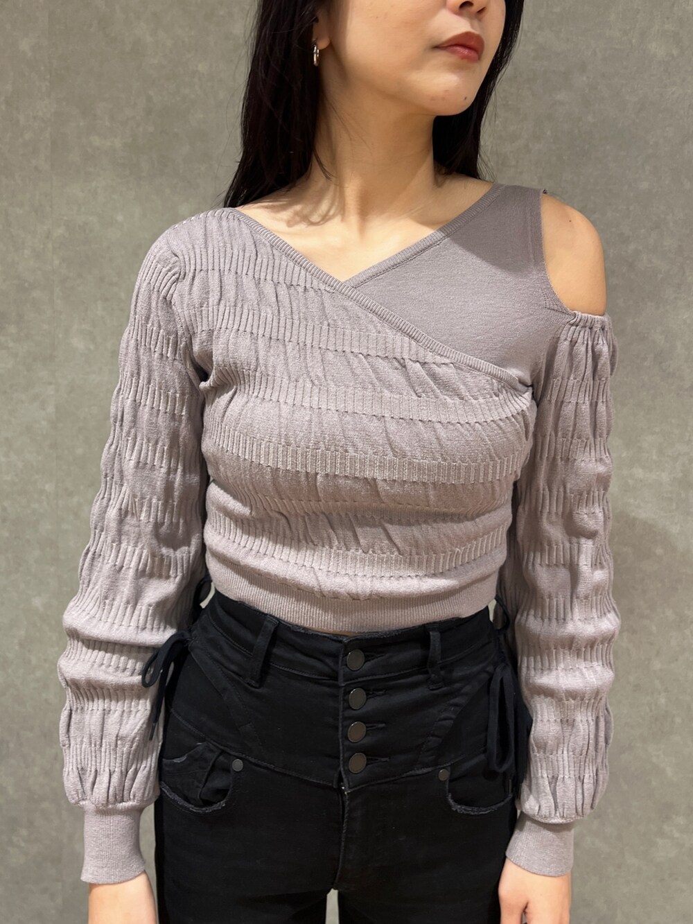 グレー系のニット/セーター、ブラック系のブーツ、ブラック系のデニムパンツを着用したレディースの春コーディネートの4枚目の写真
