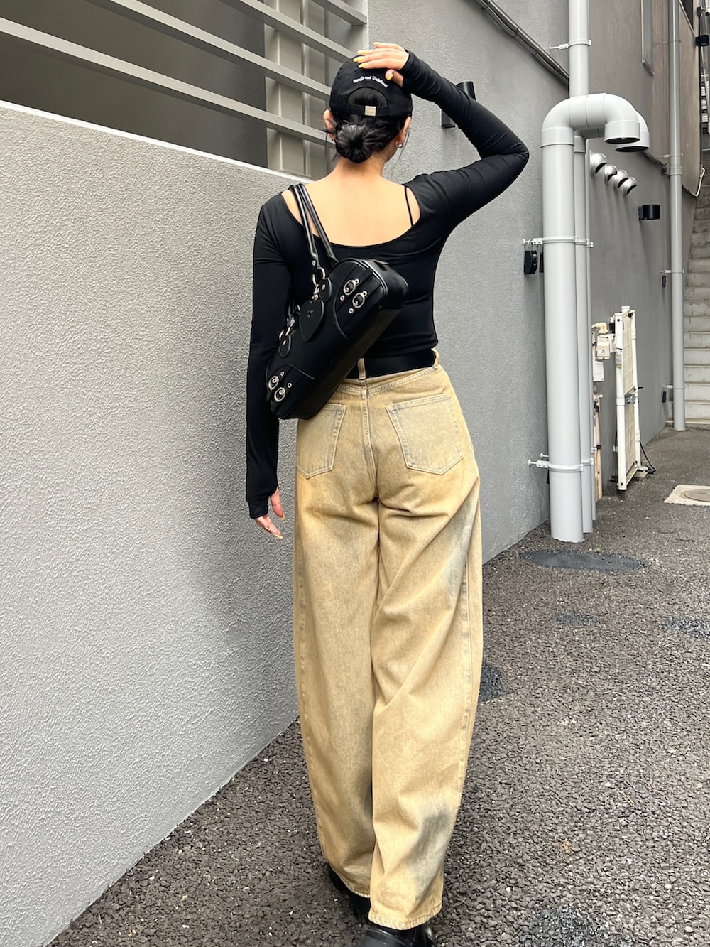 ベージュ系のデニムパンツ、ブラック系のブーツ、ブラック系のハンドバッグを着用したレディースの春コーディネートの3枚目の写真