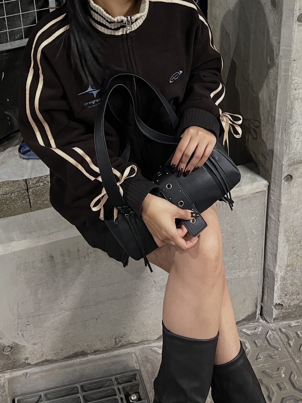 ブラウン系のブルゾン、ブラック系のブーツ、ブラウン系のスカートを着用したレディースの秋コーディネートの2枚目の写真