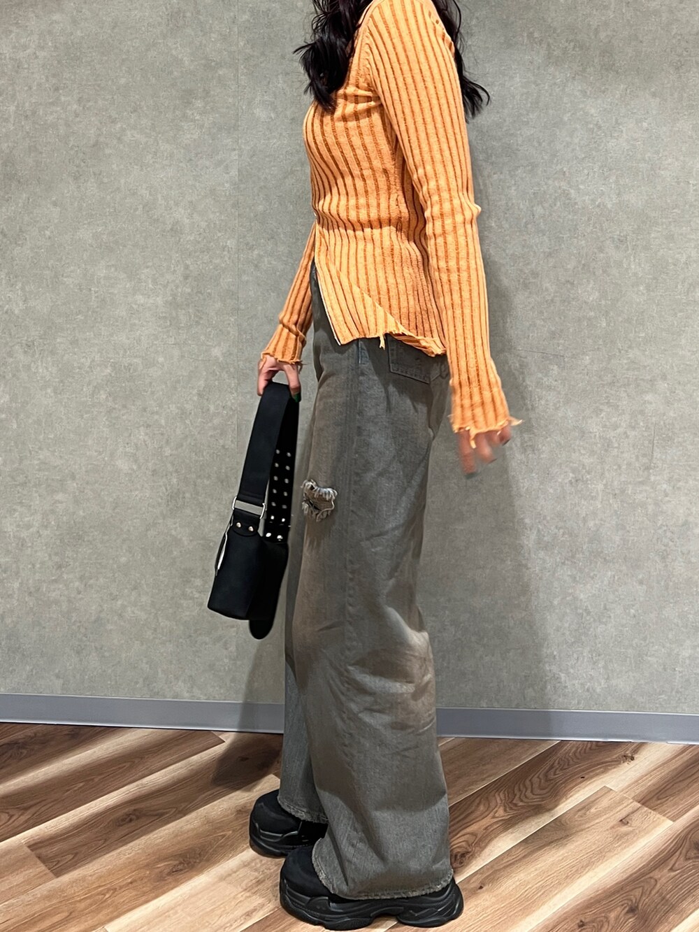 オレンジ系のニット/セーター、グレー系のデニムパンツ、ブラック系のショルダーバッグを着用したレディースの冬コーディネートの2枚目の写真