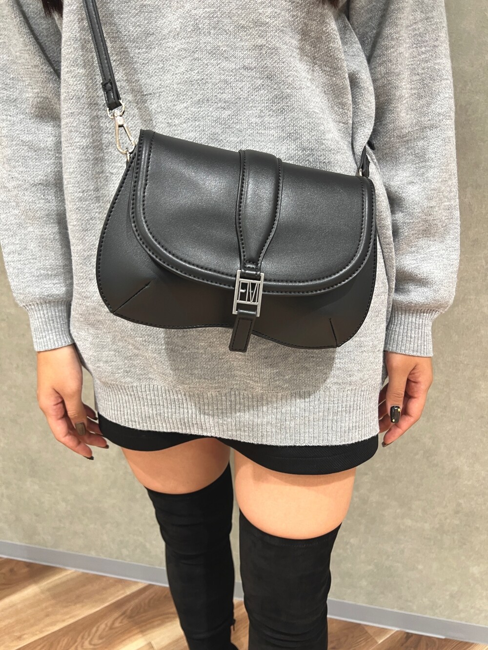 グレー系のワンピース、ブラック系のスカート、ブラック系のブーツを着用したレディースの秋コーディネートの6枚目の写真