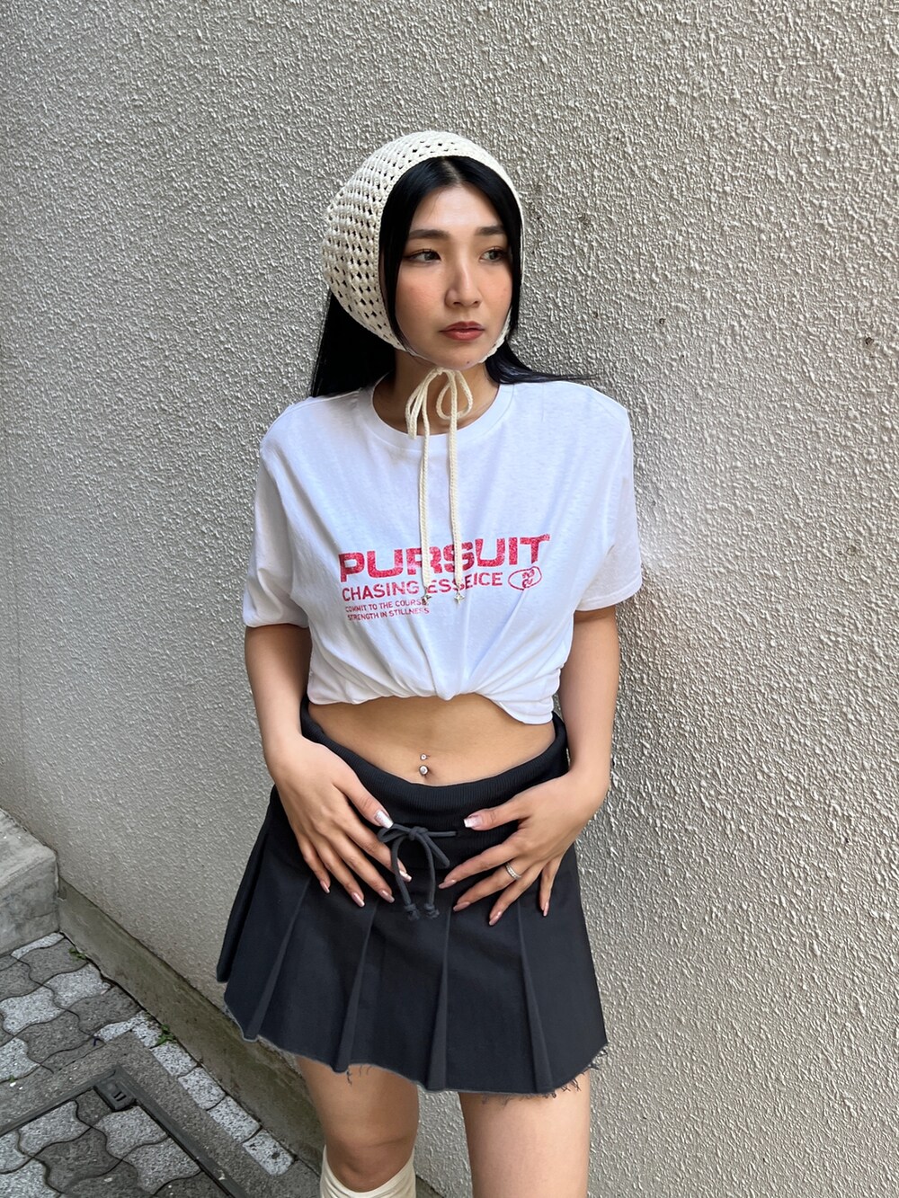 ホワイト系のTシャツ/カットソー、ブラック系のスカート、ブラック系のスニーカーを着用したレディースの春コーディネートの3枚目の写真