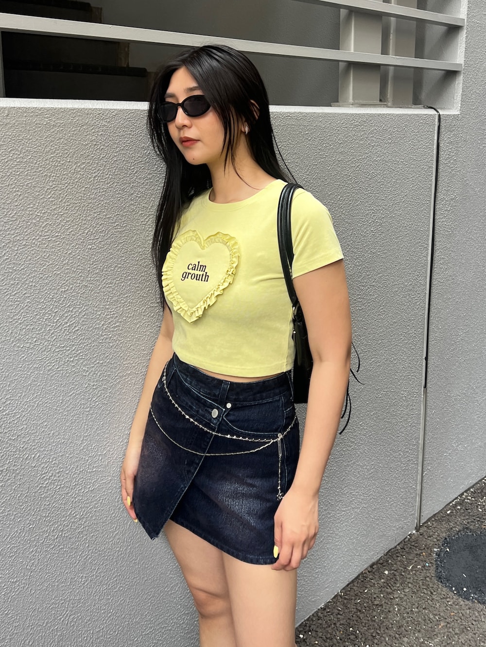 イエロー系のTシャツ/カットソー、ブルー系のスカート、ブラック系のブーツを着用したレディースの夏コーディネートの4枚目の写真