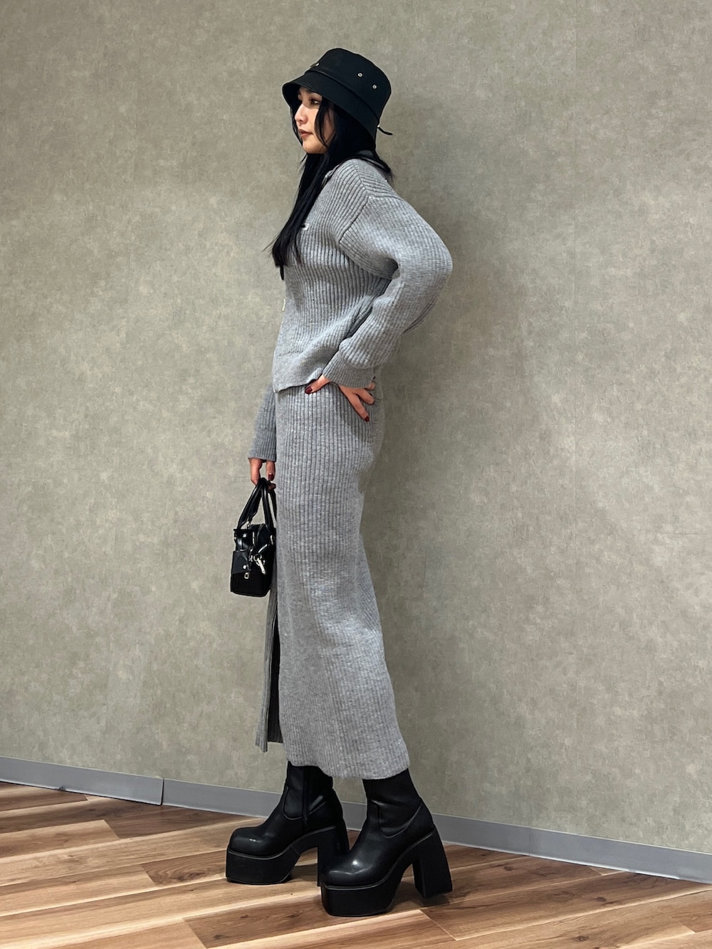 グレー系のスカート、グレー系のニット/セーター、ブラック系のブーツを着用したレディースの冬コーディネートの2枚目の写真