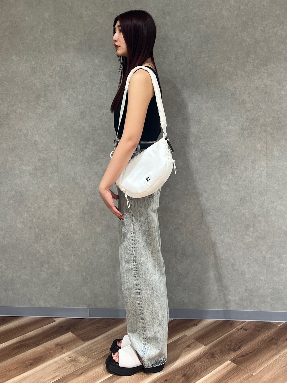 ブラック系のタンクトップ、ブルー系のデニムパンツ、ホワイト系のサンダルを着用したレディースの春コーディネートの2枚目の写真