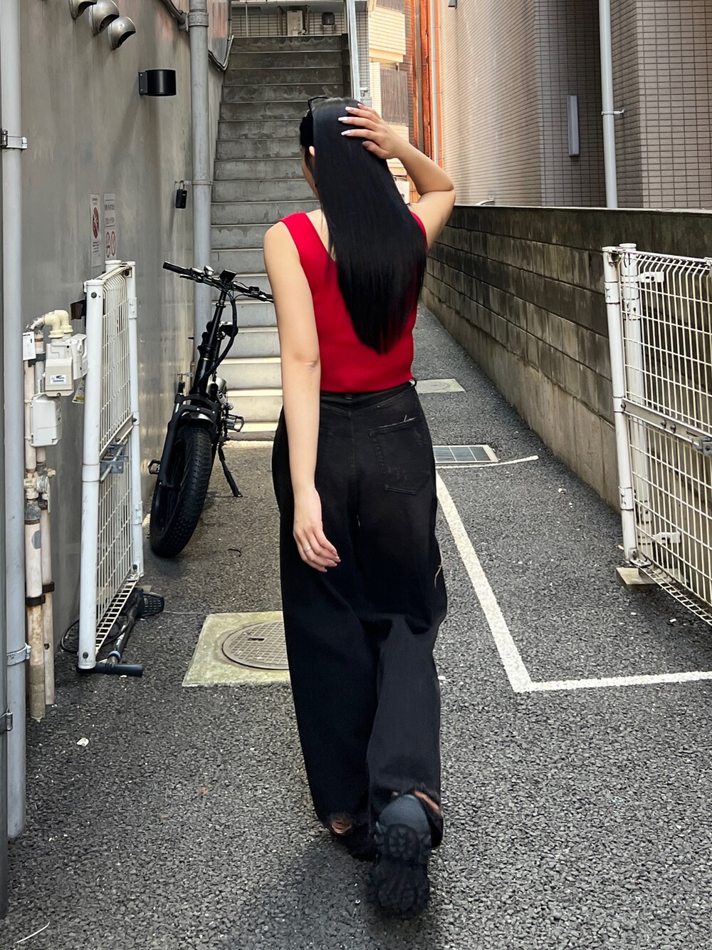 レッド系のTシャツ/カットソー、ブラック系のデニムパンツ、ブラック系のスニーカーを着用したレディースの夏コーディネートの5枚目の写真