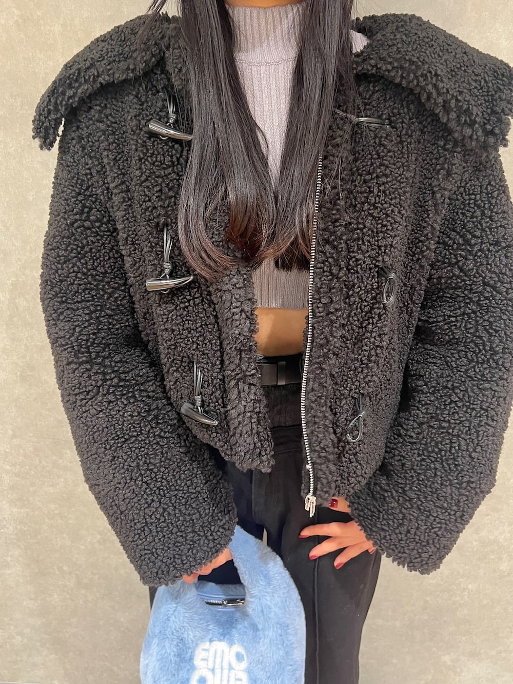 グレー系のニット/セーター、ブルー系のハンドバッグ、ブラック系のブルゾンを着用したレディースの冬コーディネートの4枚目の写真