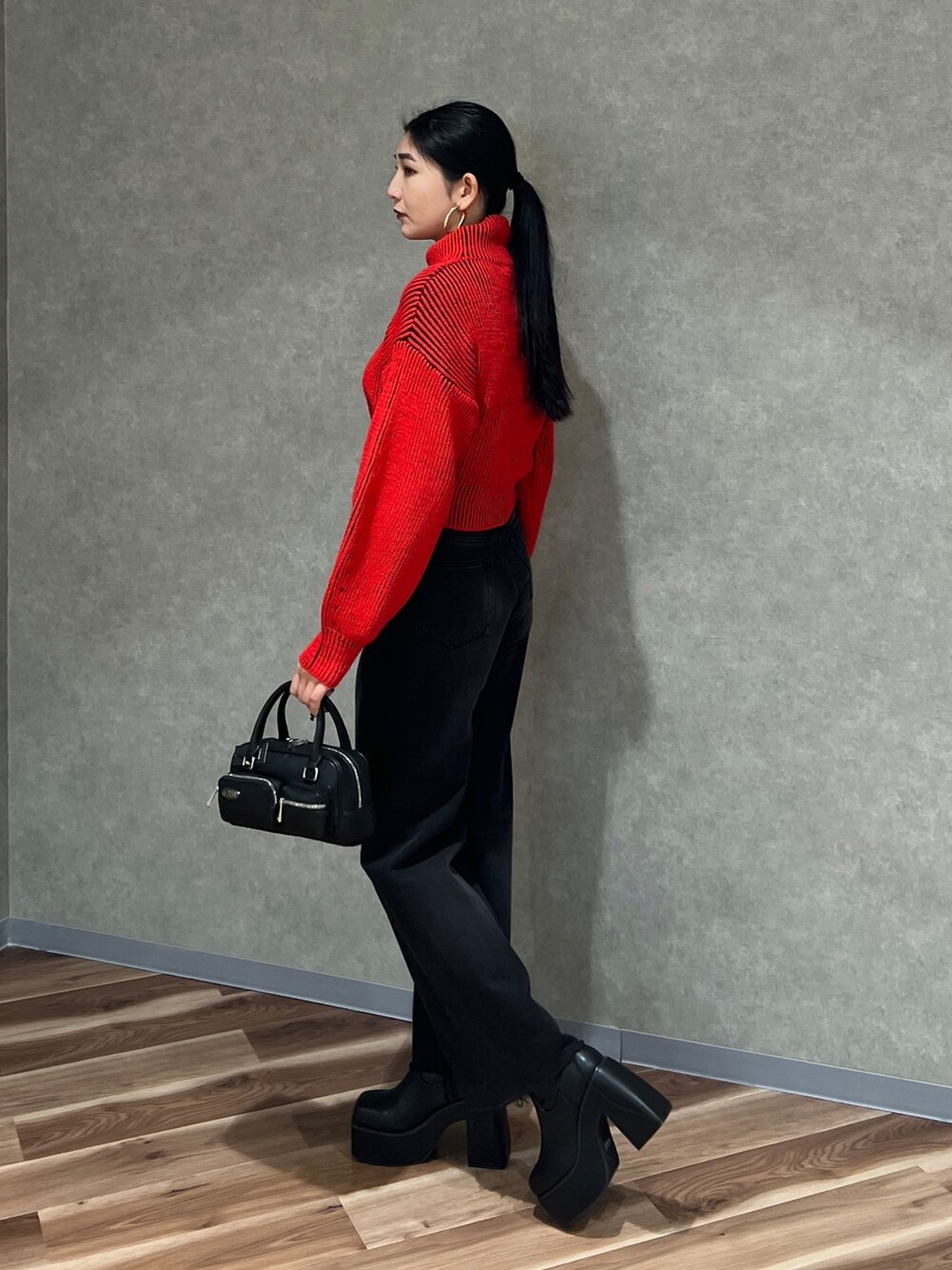 レッド系のニット/セーター、ブラック系のデニムパンツ、ブラック系のブーツを着用したレディースの秋コーディネートの4枚目の写真
