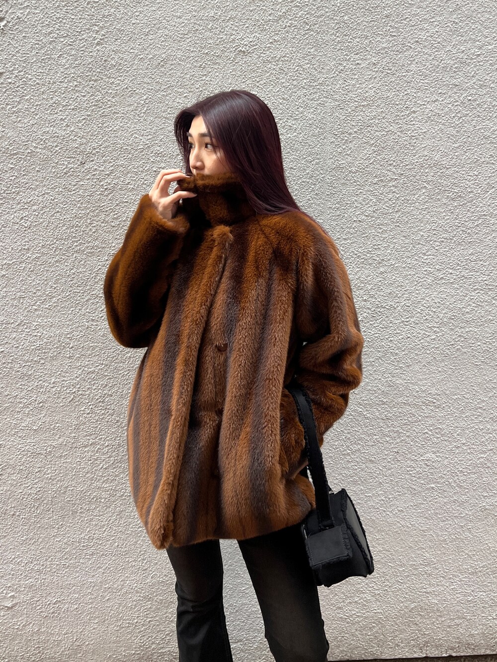 ブラウン系のその他アウター、ブラック系のニット/セーター、ブラック系のデニムパンツを着用したレディースの冬コーディネートの4枚目の写真