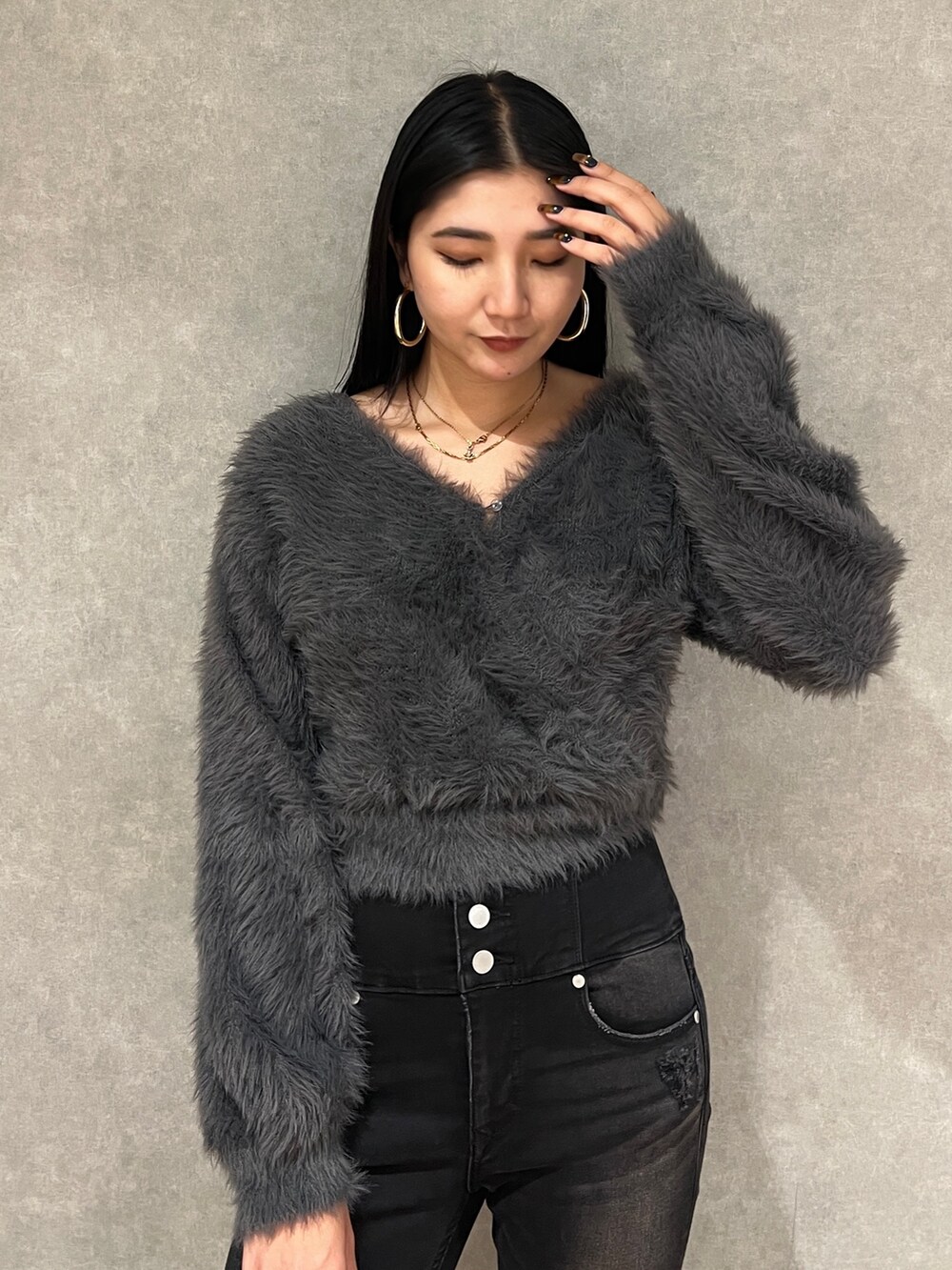 グレー系のニット/セーター、ブラック系のデニムパンツ、ブラック系のブーツを着用したレディースの秋コーディネートの9枚目の写真