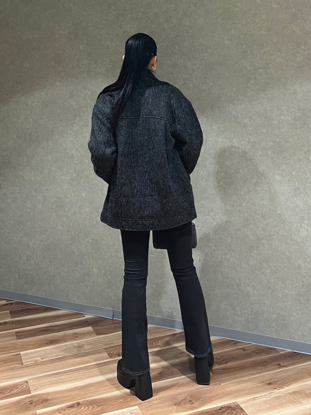 グレー系のピーコート、ブラック系のニット/セーター、ブラック系のデニムパンツを着用したレディースの秋コーディネートの3枚目の写真