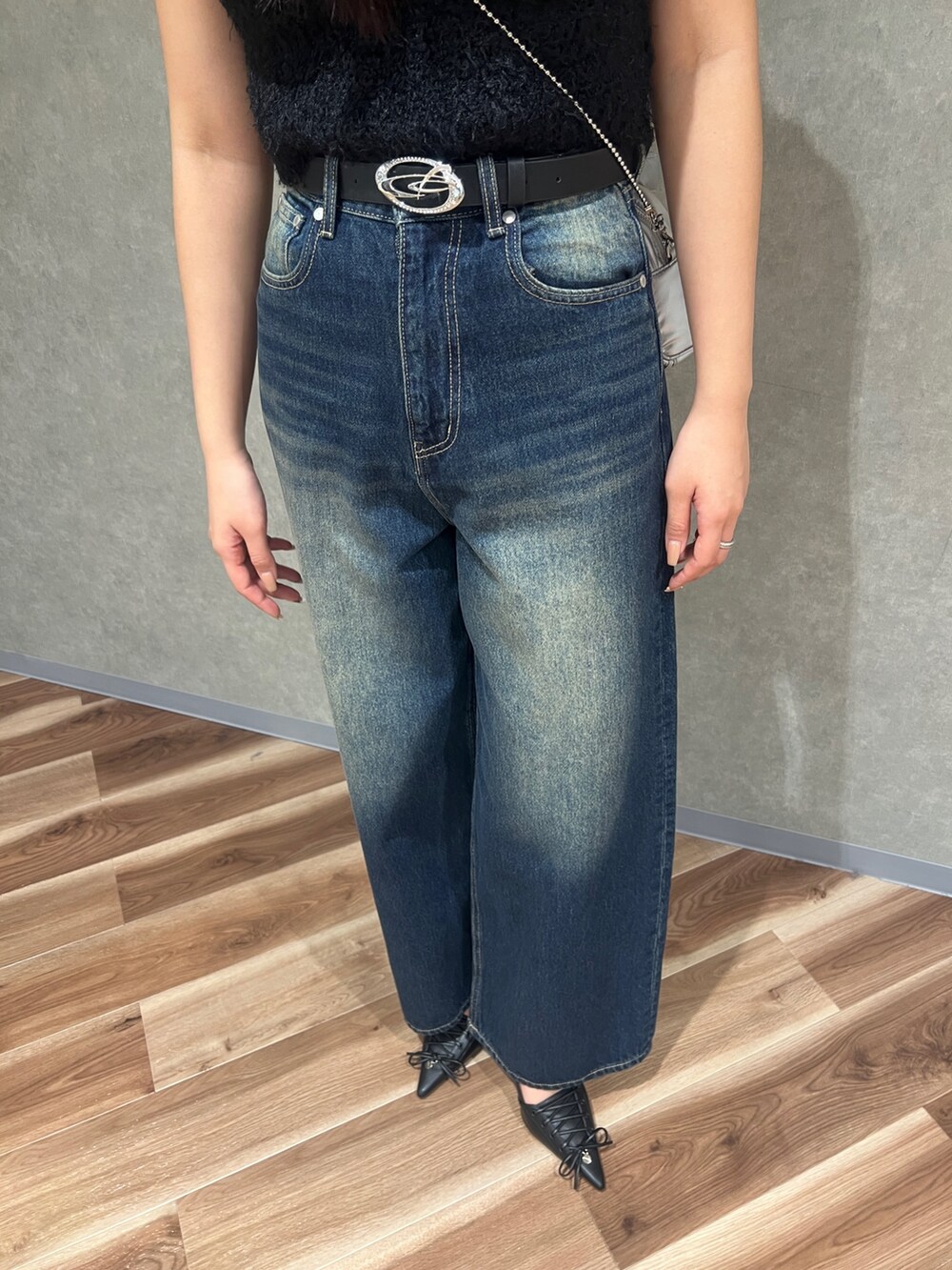 ブラック系のニット/セーター、ブルー系のデニムパンツ、ブラック系のパンプスを着用したレディースの春コーディネートの5枚目の写真