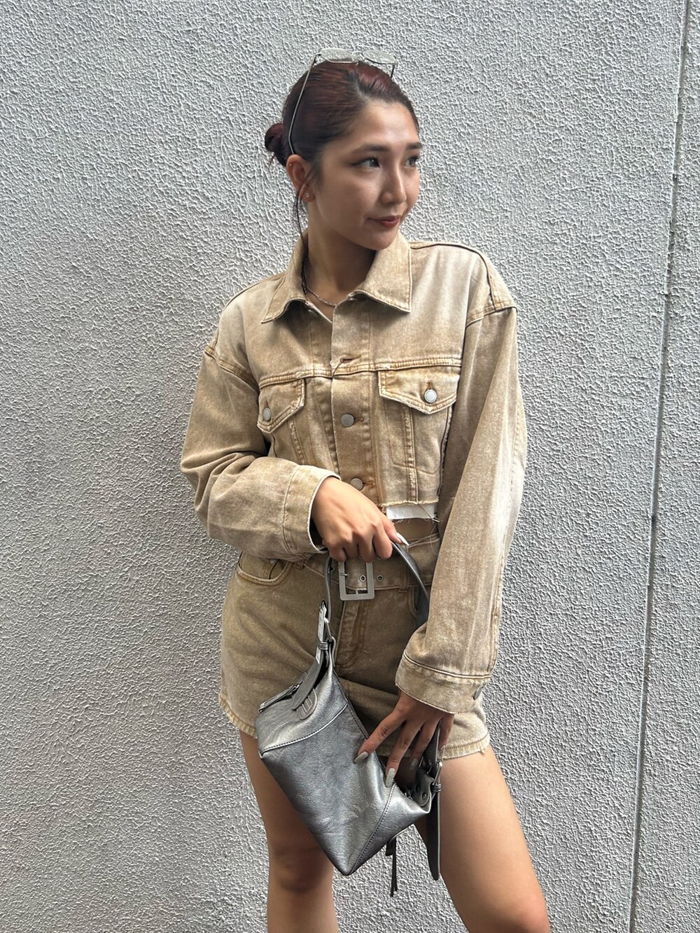 ベージュ系のデニムジャケット、ベージュ系のデニムスカート、シルバー系のハンドバッグを着用したレディースの夏コーディネートの4枚目の写真