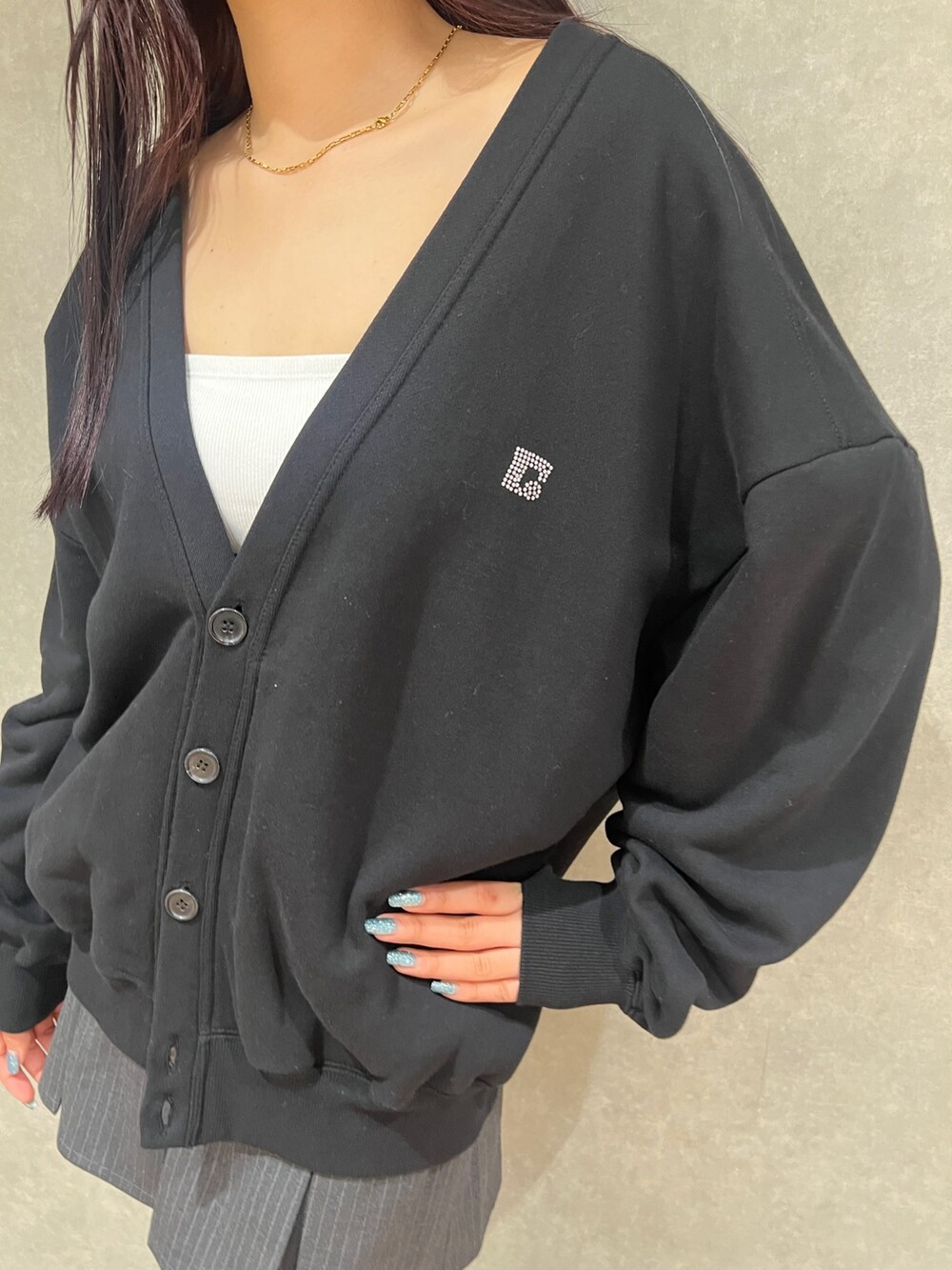 グレー系のスカート、ブラック系のカーディガン/ボレロ、ホワイト系のキャミソールを着用したレディースの春コーディネートの4枚目の写真