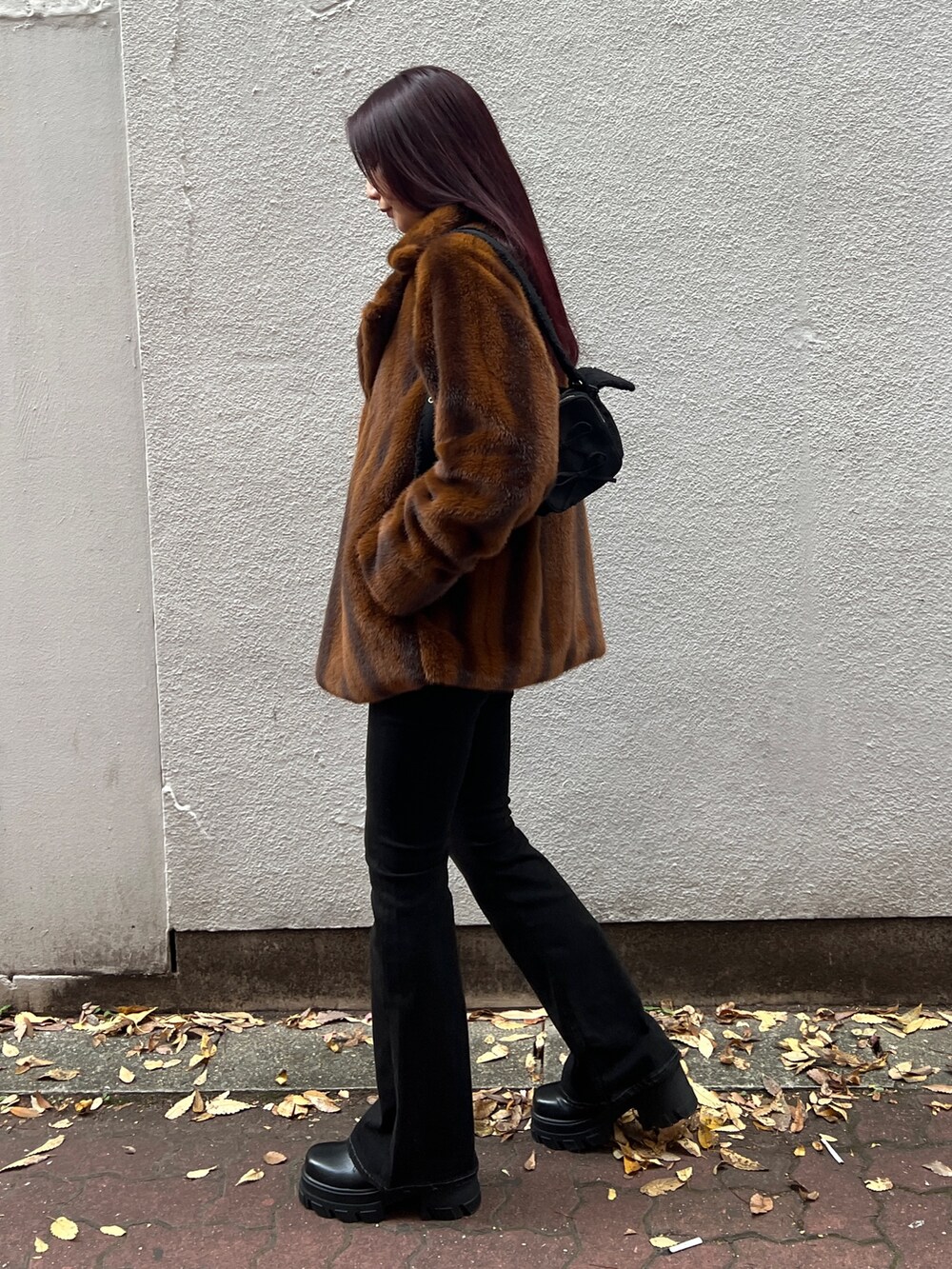 ブラウン系のその他アウター、ブラック系のニット/セーター、ブラック系のデニムパンツを着用したレディースの冬コーディネートの2枚目の写真