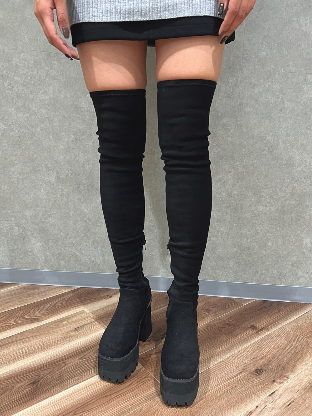 グレー系のワンピース、ブラック系のスカート、ブラック系のブーツを着用したレディースの秋コーディネートの5枚目の写真