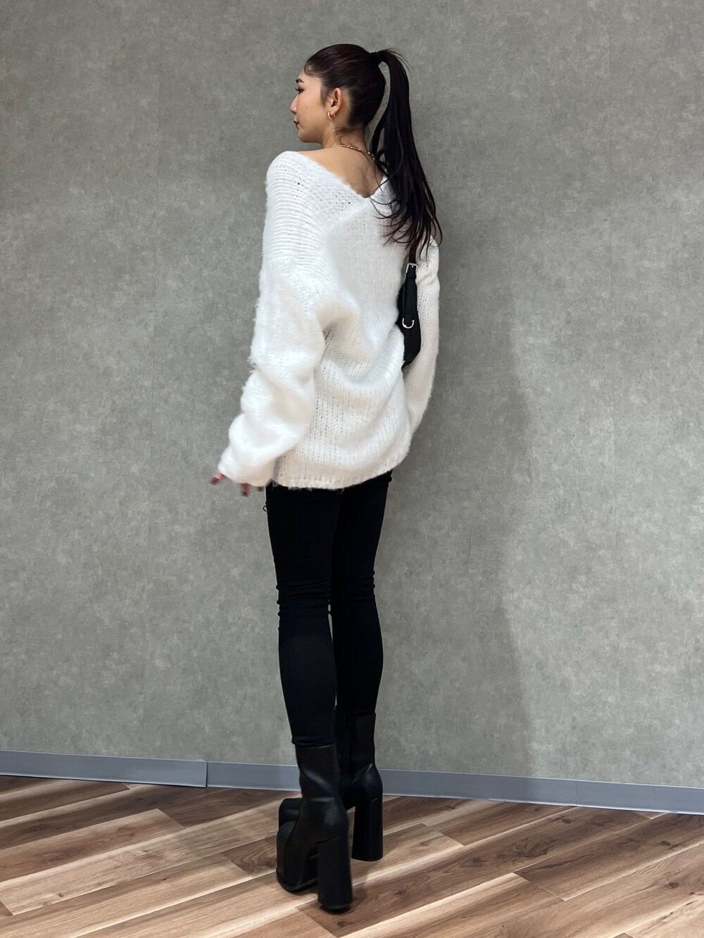 ホワイト系のニット/セーター、ブラック系のデニムパンツ、ブラック系のハンドバッグを着用したレディースの冬コーディネートの3枚目の写真