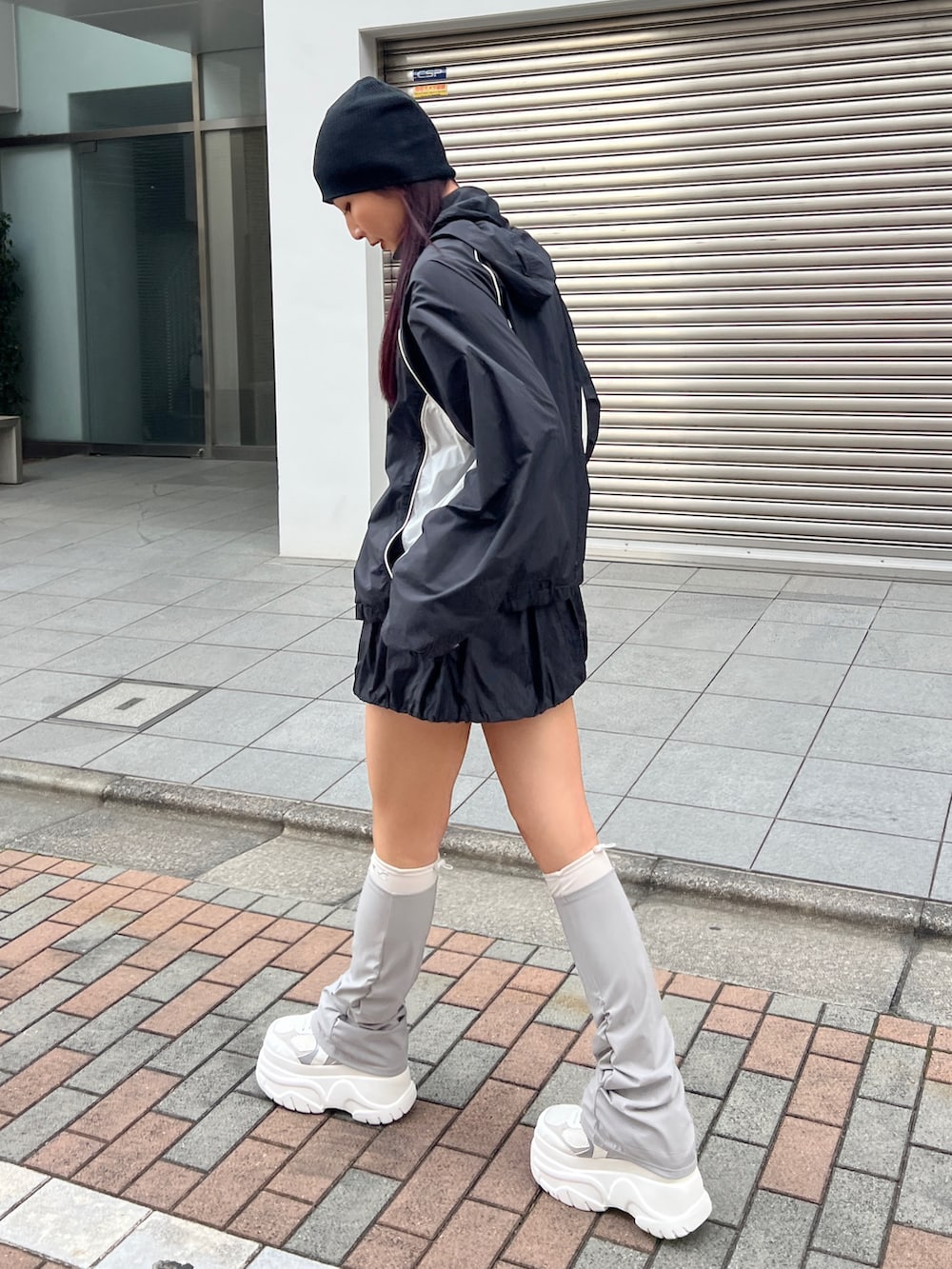 ブラック系のブルゾン、ブラック系のスカート、ホワイト系のスニーカーを着用したレディースの冬コーディネートの4枚目の写真