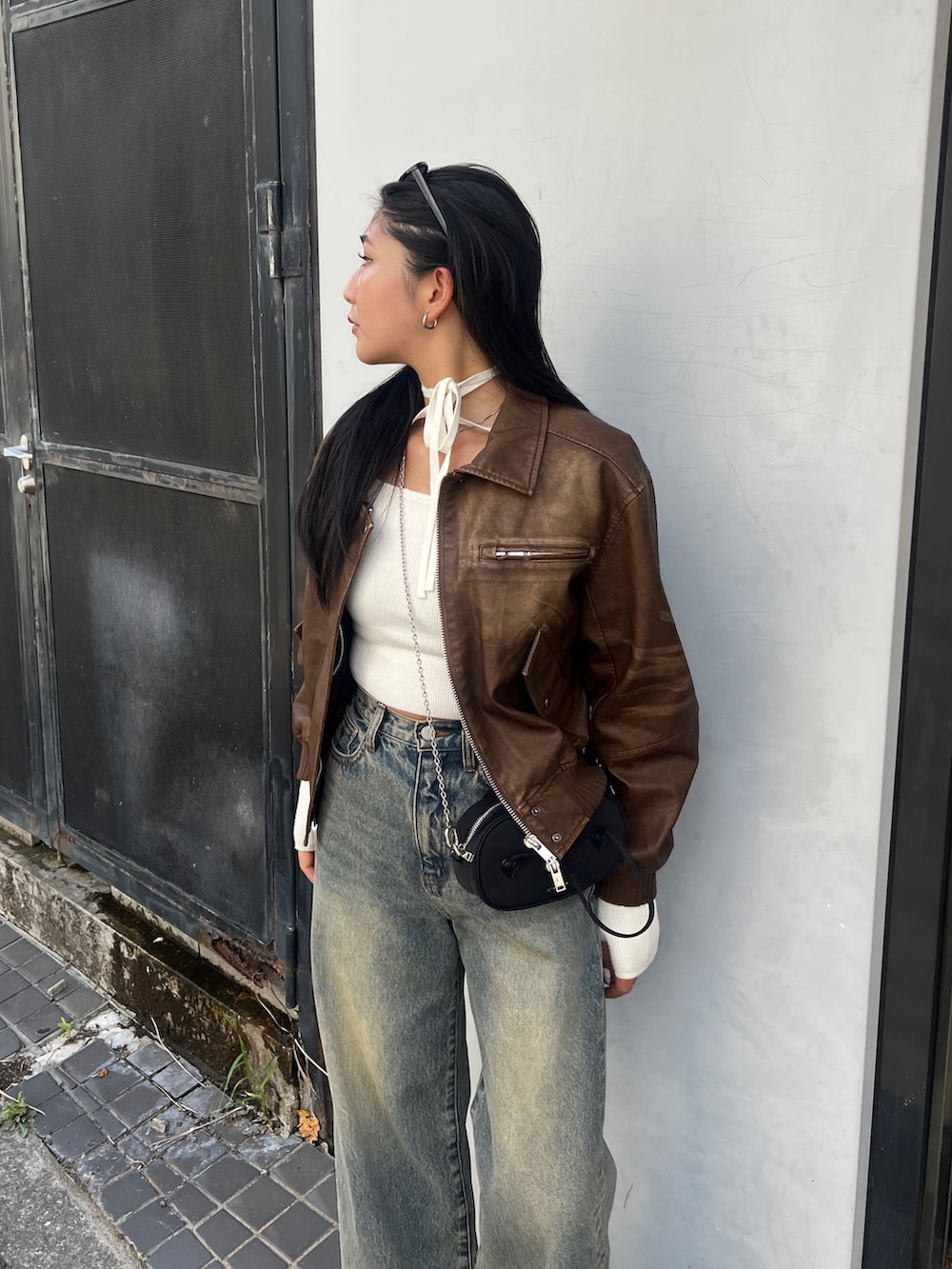 ブラウン系のブルゾン、ホワイト系のニット/セーター、ブルー系のデニムパンツを着用したレディースの秋コーディネートの4枚目の写真