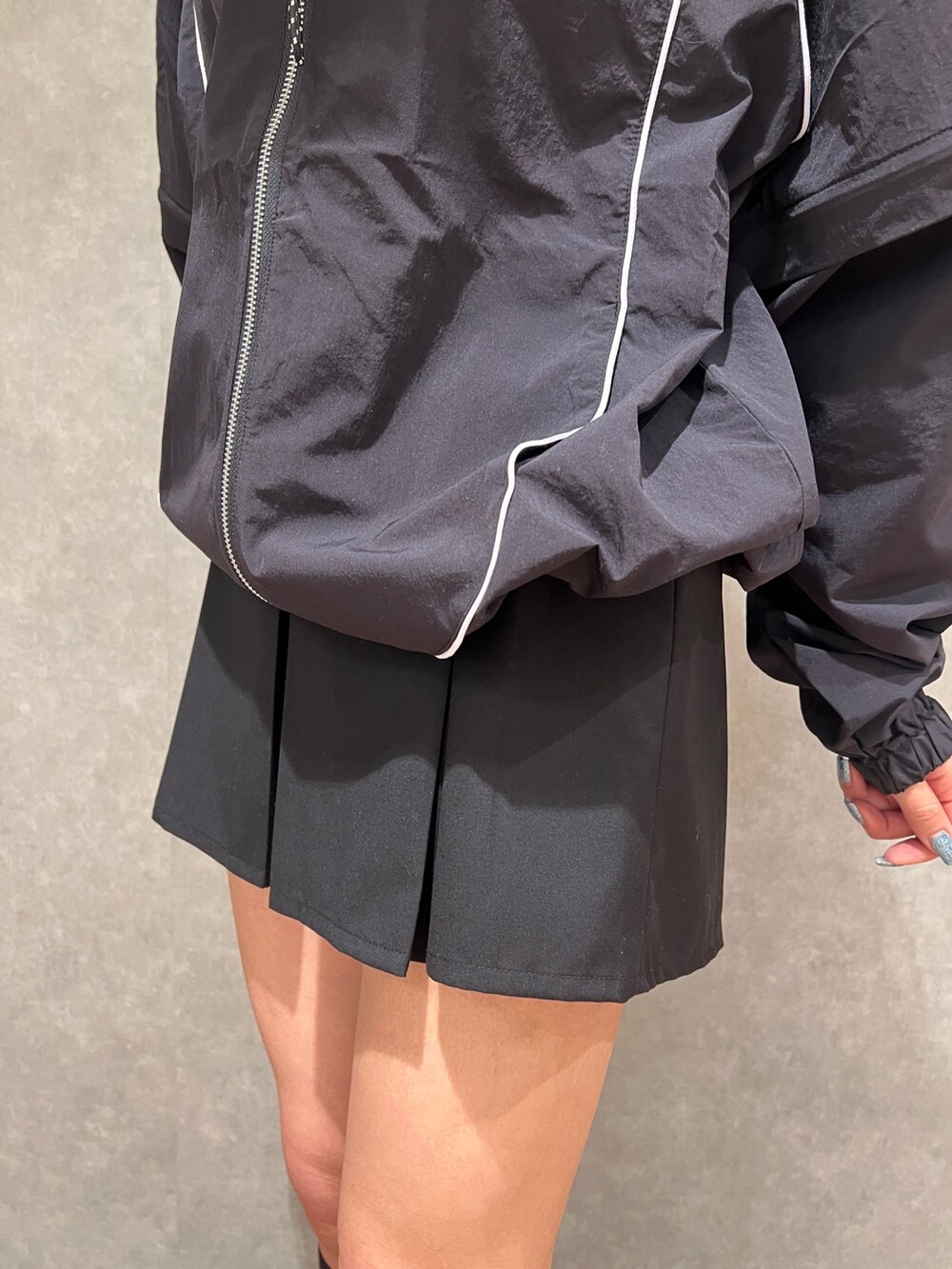 ブラック系のブルゾン、ブラック系のスカート、ブラック系のブーツを着用したレディースの春コーディネートの6枚目の写真