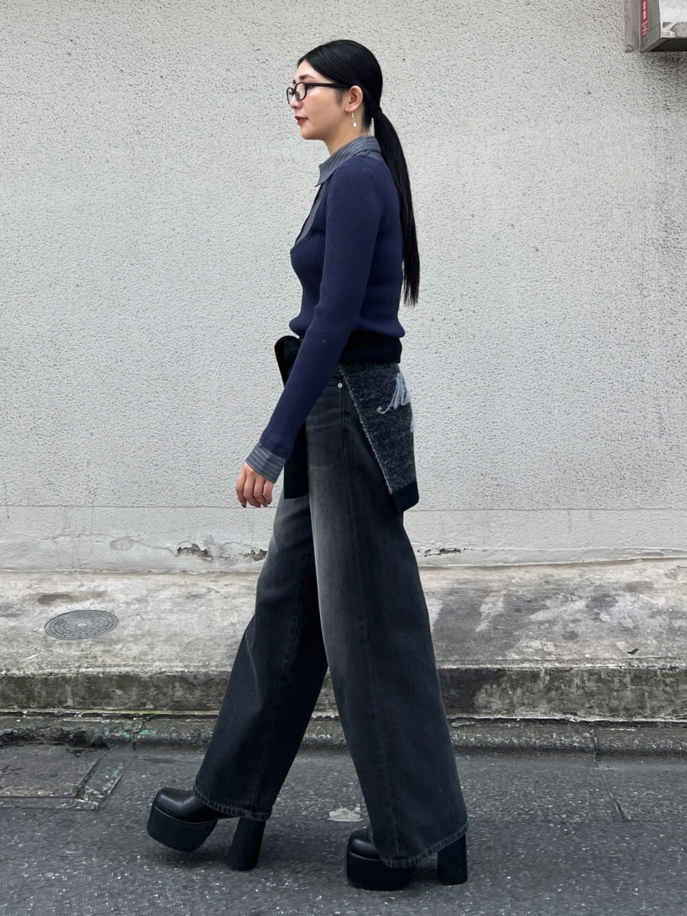 ブルー系のニット/セーター、ブラック系のブーツ、ブラック系のデニムパンツを着用したレディースの夏コーディネートの2枚目の写真