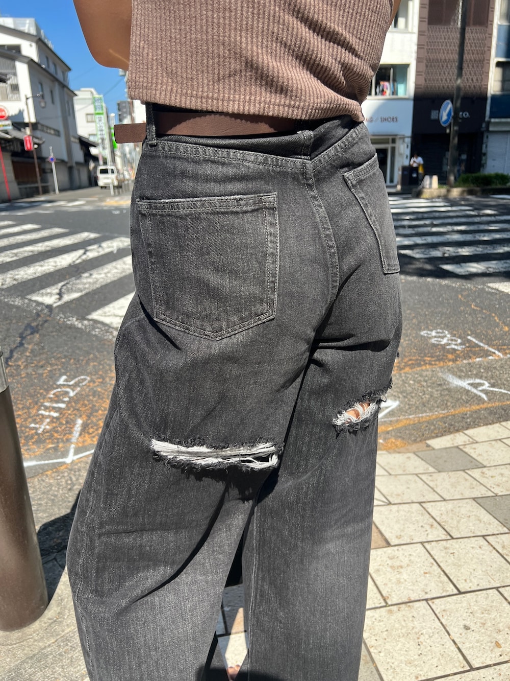 ブラック系のタンクトップ、ブラック系のデニムパンツ、グレー系のハンドバッグを着用したレディースの夏コーディネートの5枚目の写真