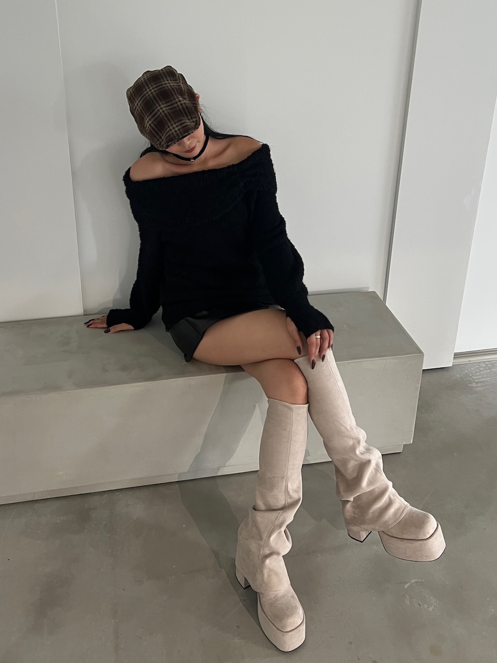 ブラック系のニット/セーター、ブラック系のスカート、ホワイト系のブーツを着用したレディースの秋コーディネートの4枚目の写真