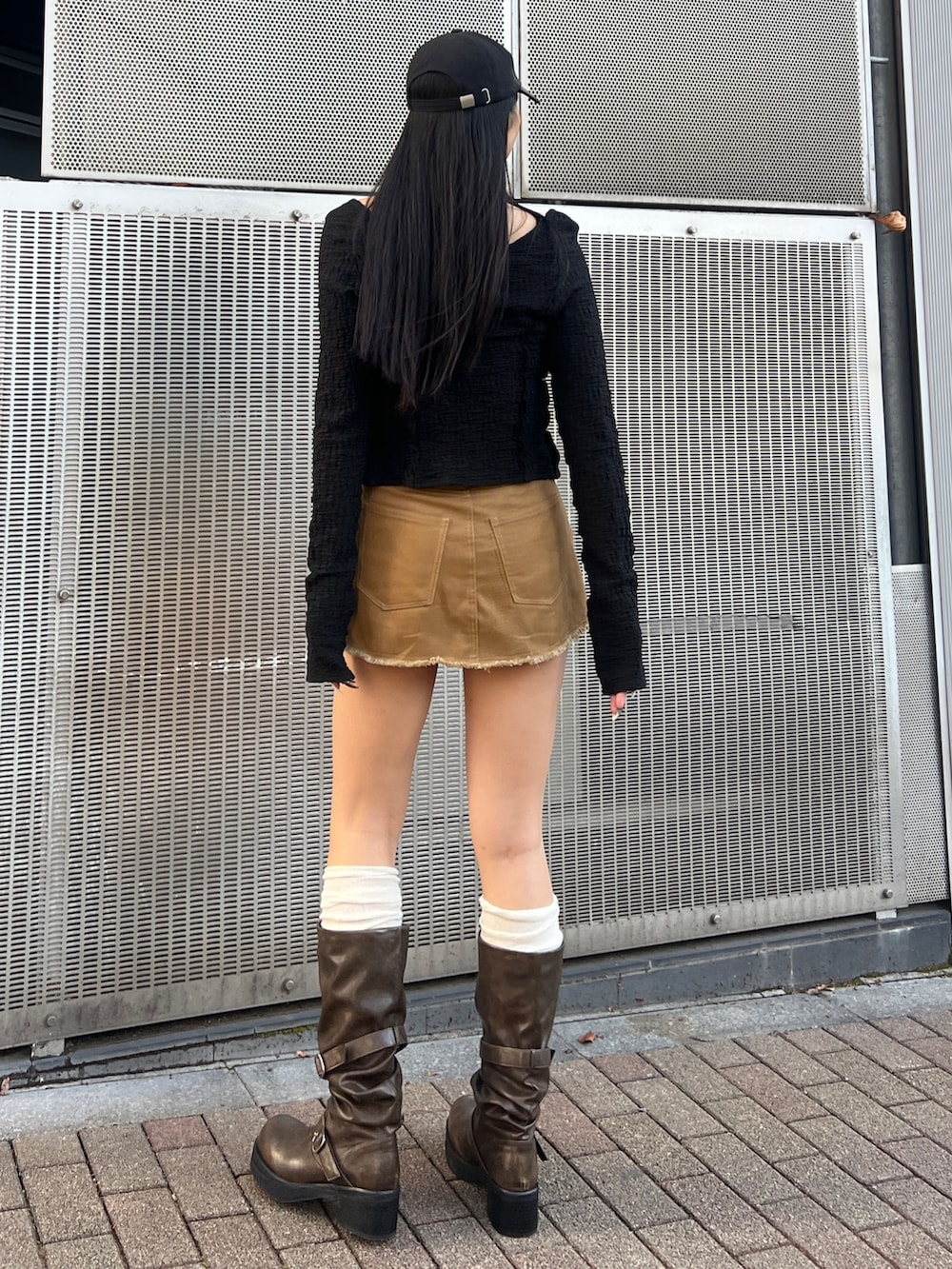 ブラック系のTシャツ/カットソー、ブラウン系のブーツ、ブラック系のキャップを着用したレディースの冬コーディネートの3枚目の写真