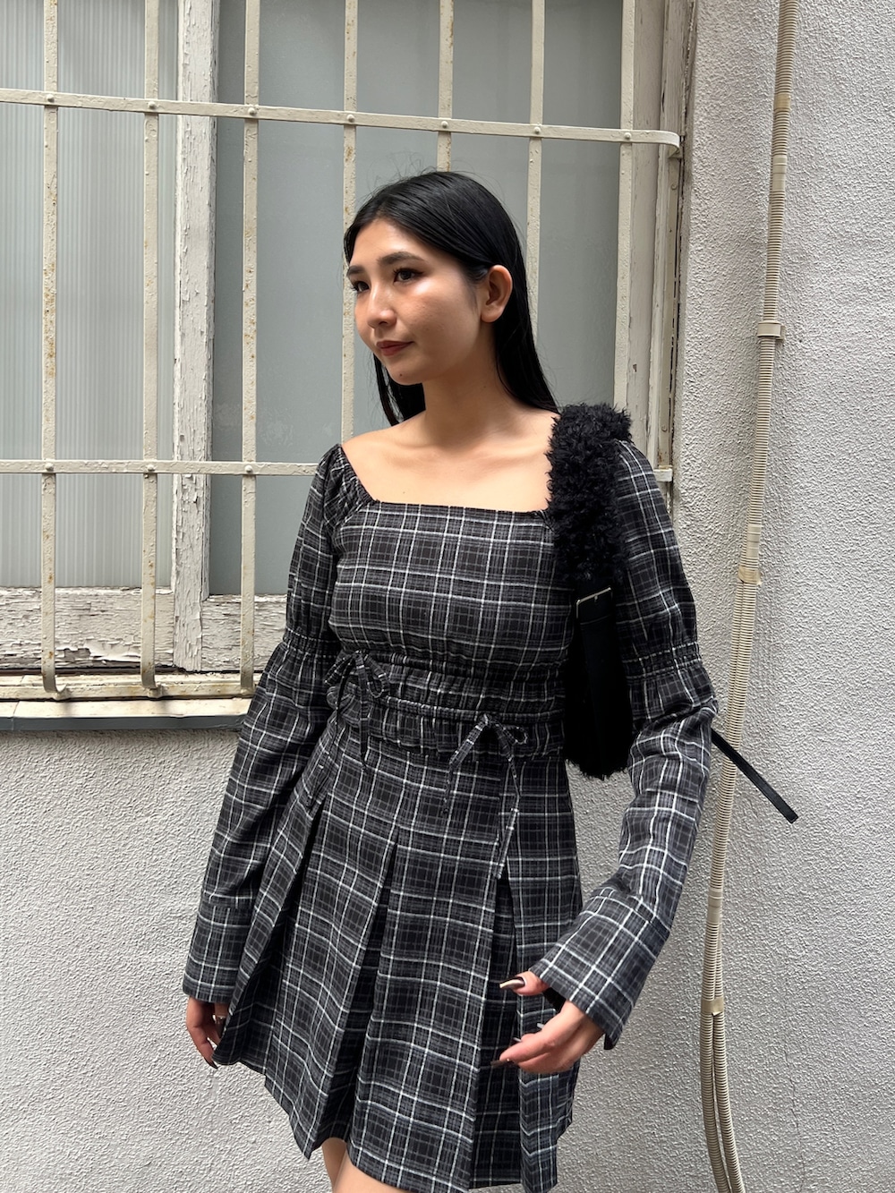 グレー系のワンピース、ブラック系のブーツ、ブラック系のショルダーバッグを着用したレディースの冬コーディネートの4枚目の写真