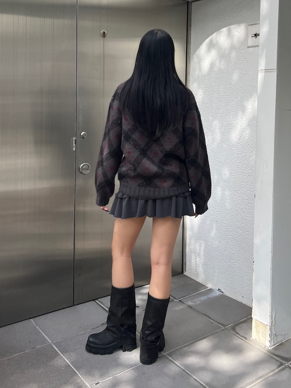 グレー系のニット/セーター、グレー系のスカート、ブラック系のブーツを着用したレディースの秋コーディネートの3枚目の写真