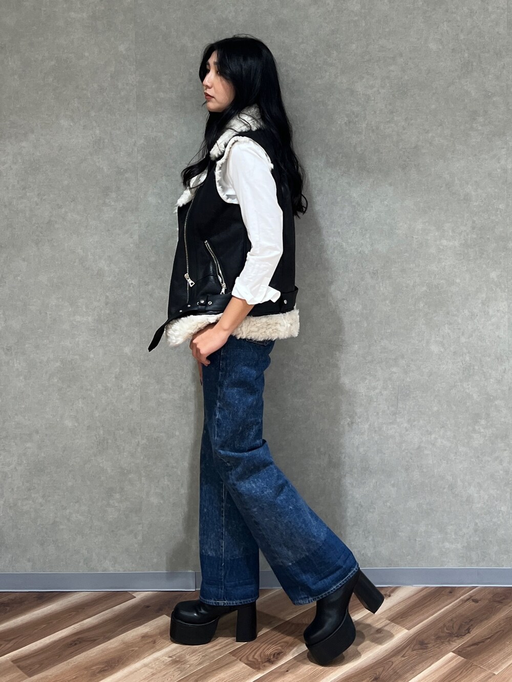 ブラック系のムートンコート、ホワイト系のシャツ/ブラウス、ブルー系のデニムパンツを着用したレディースの秋コーディネートの2枚目の写真