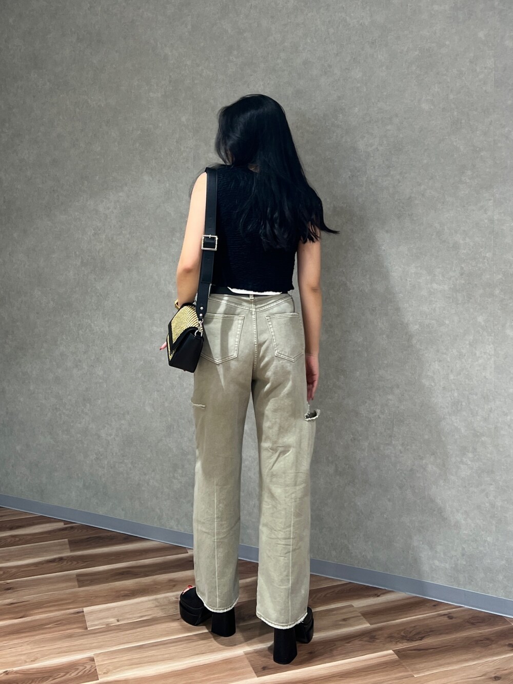 ブラック系のベスト、ホワイト系のニット/セーター、ベージュ系のデニムパンツを着用したレディースの夏コーディネートの3枚目の写真