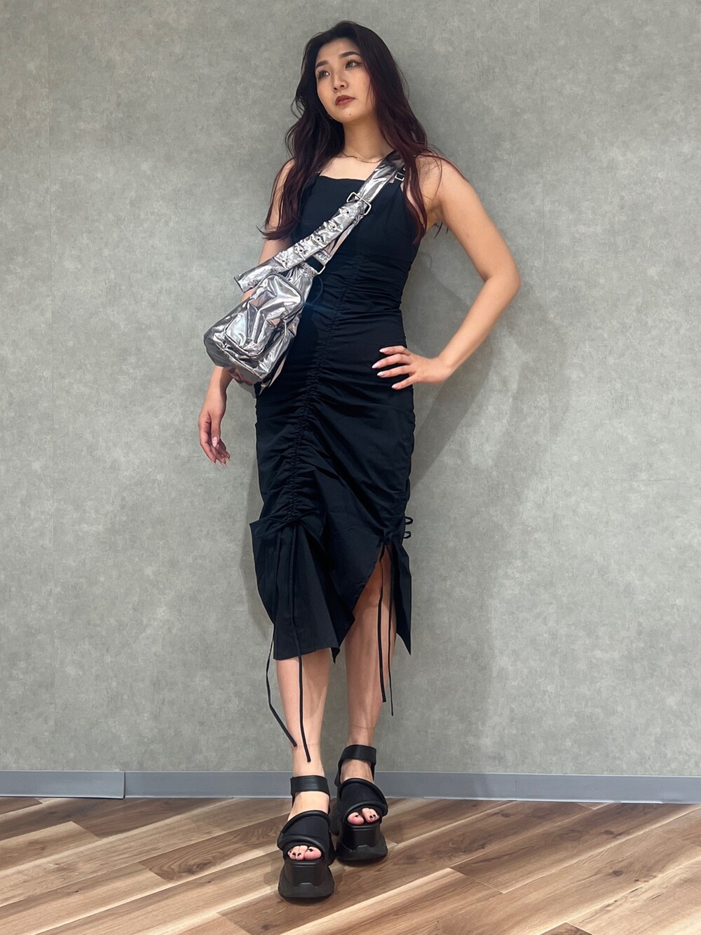 ブラック系のワンピース、シルバー系のハンドバッグ、ブラック系のサンダルを着用したレディースの夏コーディネートの2枚目の写真