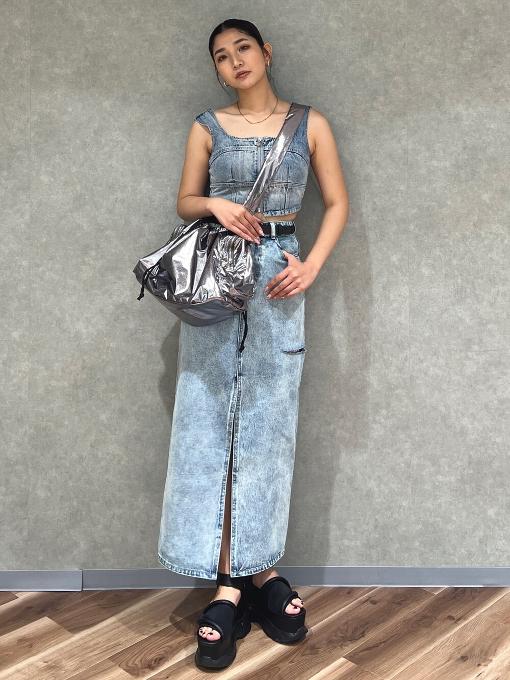 ブルー系のキャミソール、ブルー系のデニムスカート、シルバー系のハンドバッグを着用したレディースの夏コーディネートの2枚目の写真