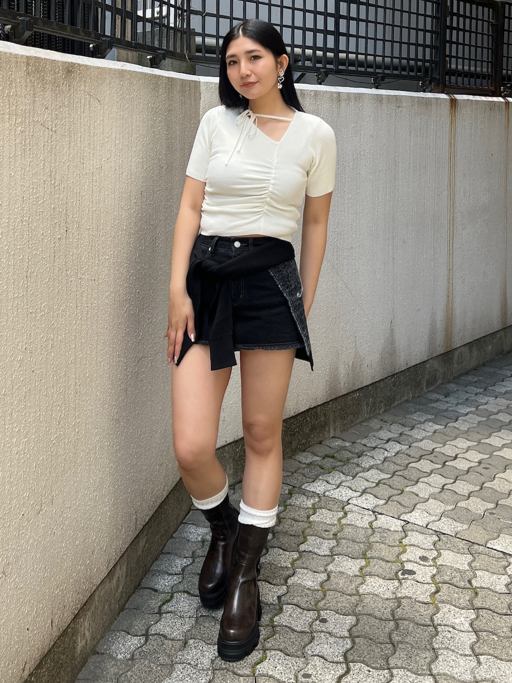 ホワイト系のニット/セーター、ブラック系のスカート、ブラウン系のブーツを着用したレディースの夏コーディネートの3枚目の写真