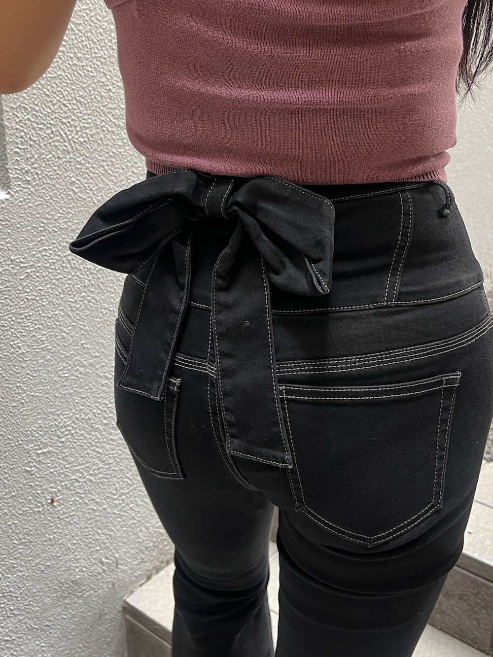 レッド系のニット/セーター、ブラック系のデニムパンツ、ブラック系のブーツを着用したレディースの夏コーディネートの4枚目の写真