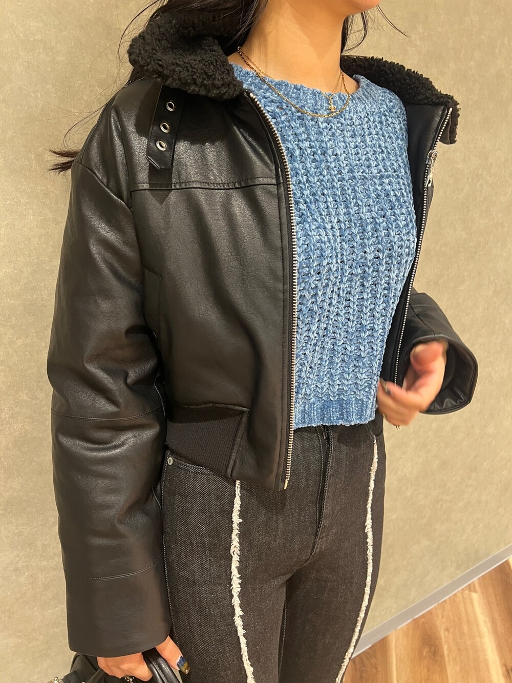 ブラック系のブルゾン、ブルー系のニット/セーター、ブラック系のデニムパンツを着用したレディースの秋コーディネートの4枚目の写真