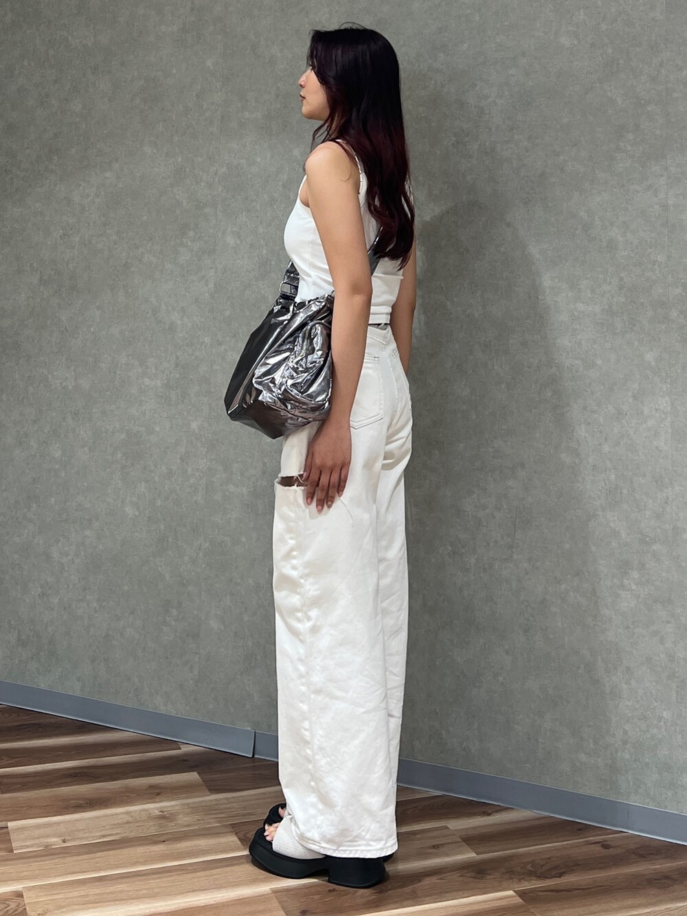 ホワイト系のタンクトップ、ホワイト系のデニムパンツ、シルバー系のハンドバッグを着用したレディースの夏コーディネートの2枚目の写真