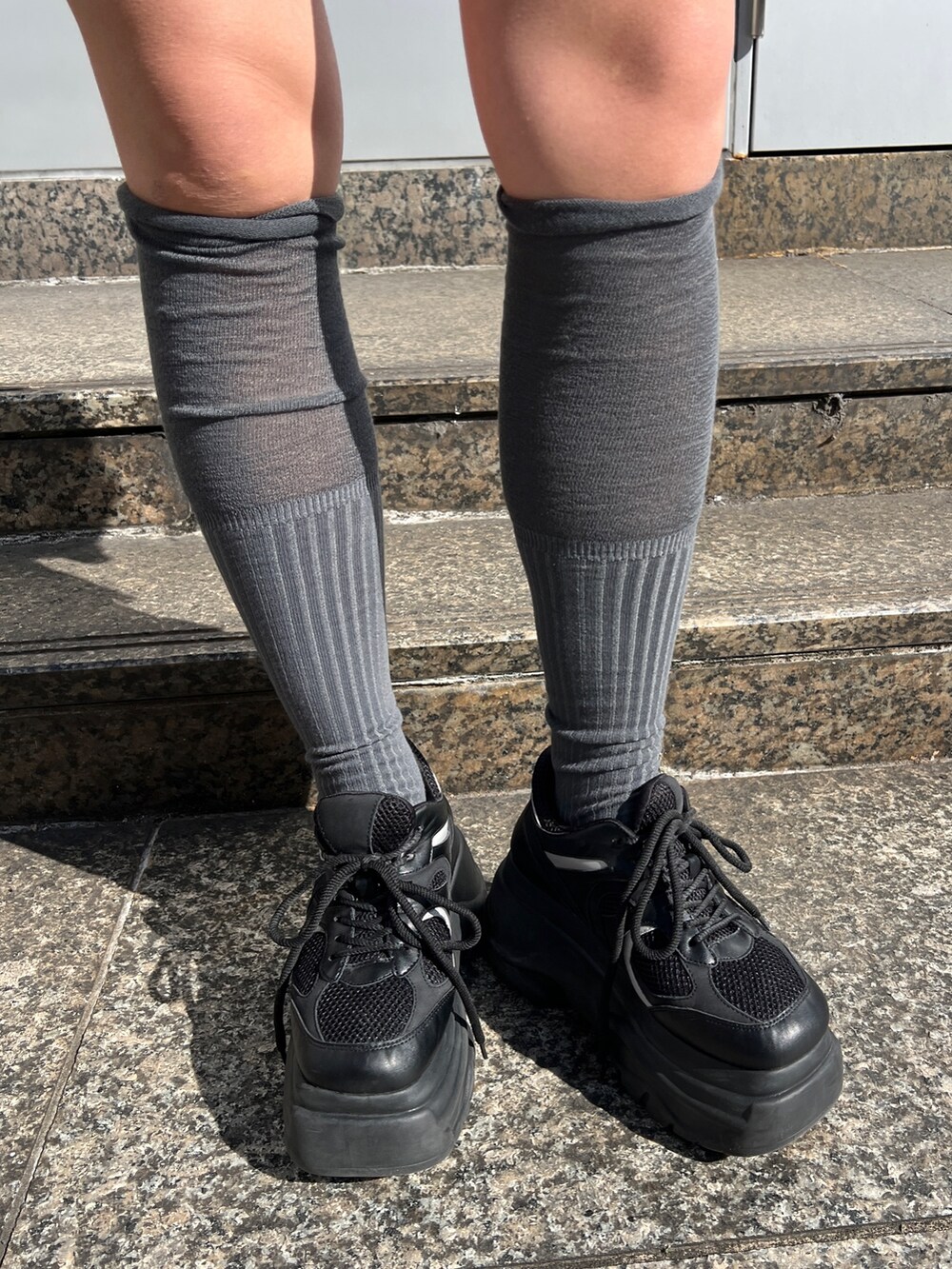 ブラック系のニット/セーター、ブルー系のその他パンツ、ブラック系のスニーカーを着用したレディースの春コーディネートの7枚目の写真
