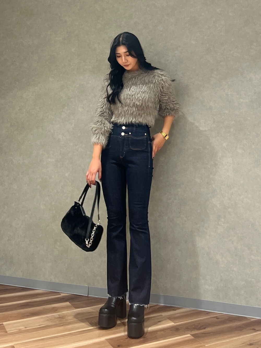 グレー系のニット/セーター、ブルー系のデニムパンツ、ブラック系のハンドバッグを着用したレディースの秋コーディネートの2枚目の写真