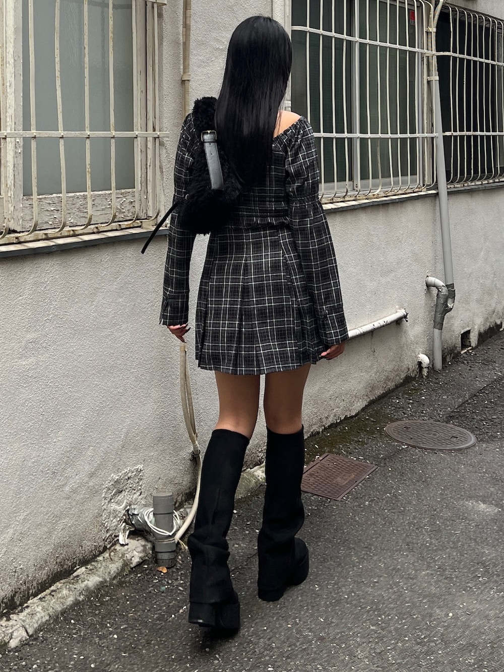 グレー系のワンピース、ブラック系のブーツ、ブラック系のショルダーバッグを着用したレディースの冬コーディネートの3枚目の写真