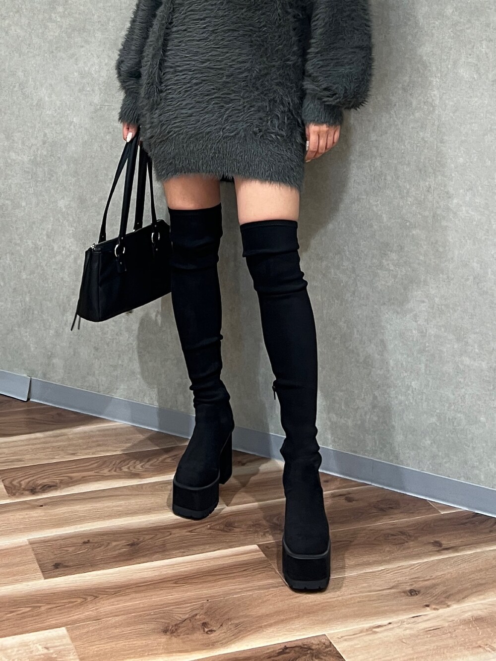 グレー系のワンピース、ブラック系のショルダーバッグ、ブラック系のブーツを着用したレディースの秋コーディネートの7枚目の写真