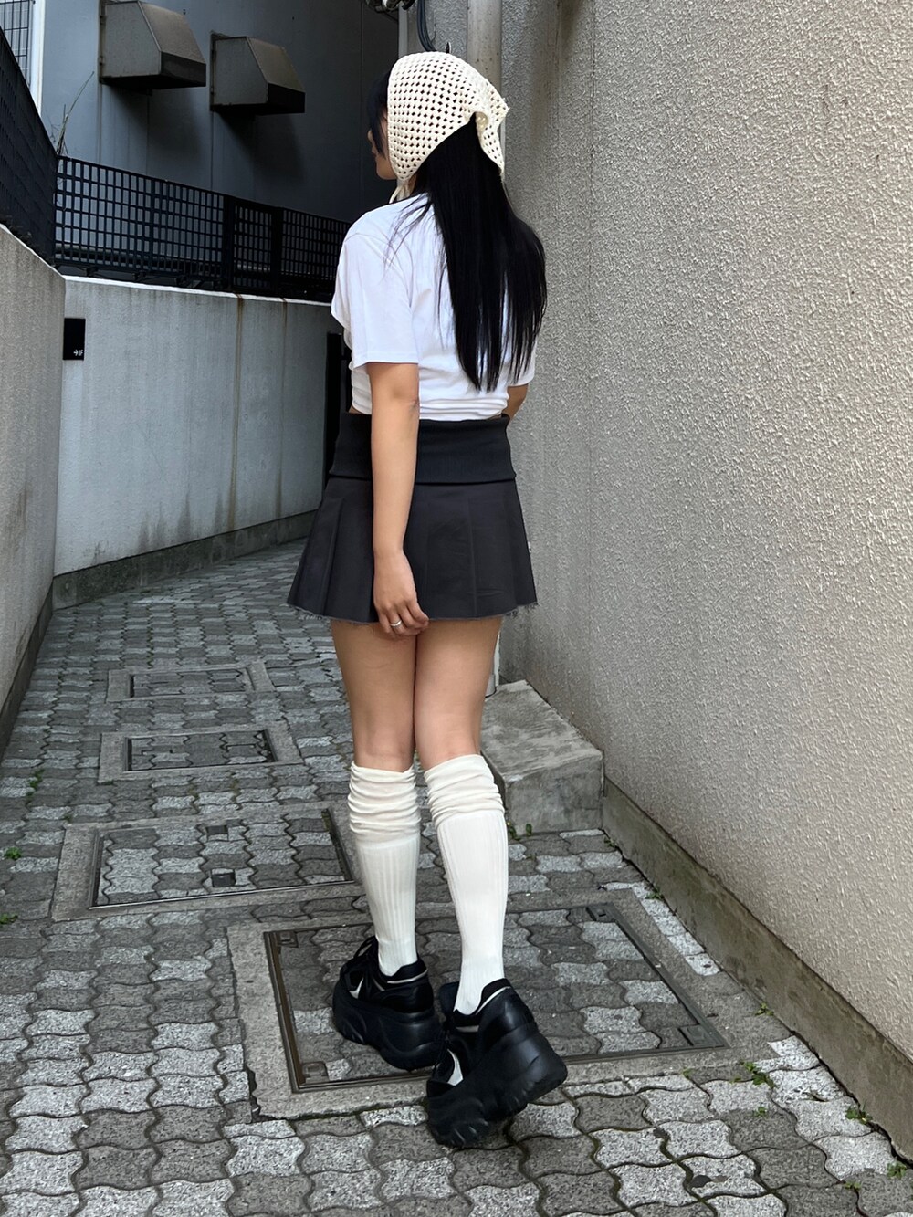 ホワイト系のTシャツ/カットソー、ブラック系のスカート、ブラック系のスニーカーを着用したレディースの春コーディネートの2枚目の写真