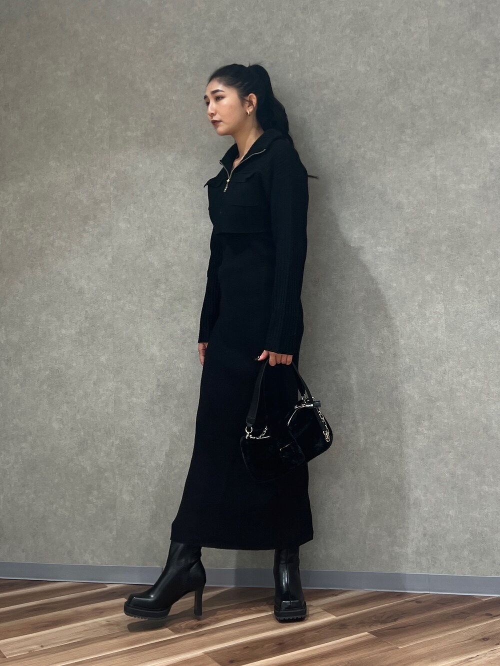 ブラック系のワンピース、ブラック系のハンドバッグ、ブラック系のブーツを着用したレディースの秋コーディネートの2枚目の写真