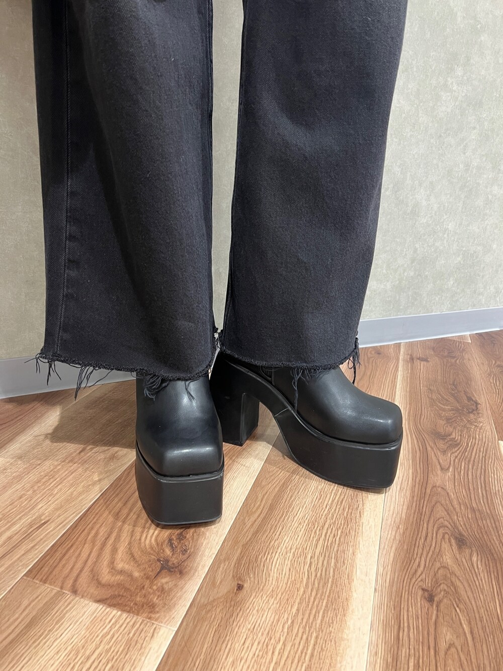 レッド系のニット/セーター、ブラック系のデニムパンツ、ブラック系のブーツを着用したレディースの秋コーディネートの8枚目の写真