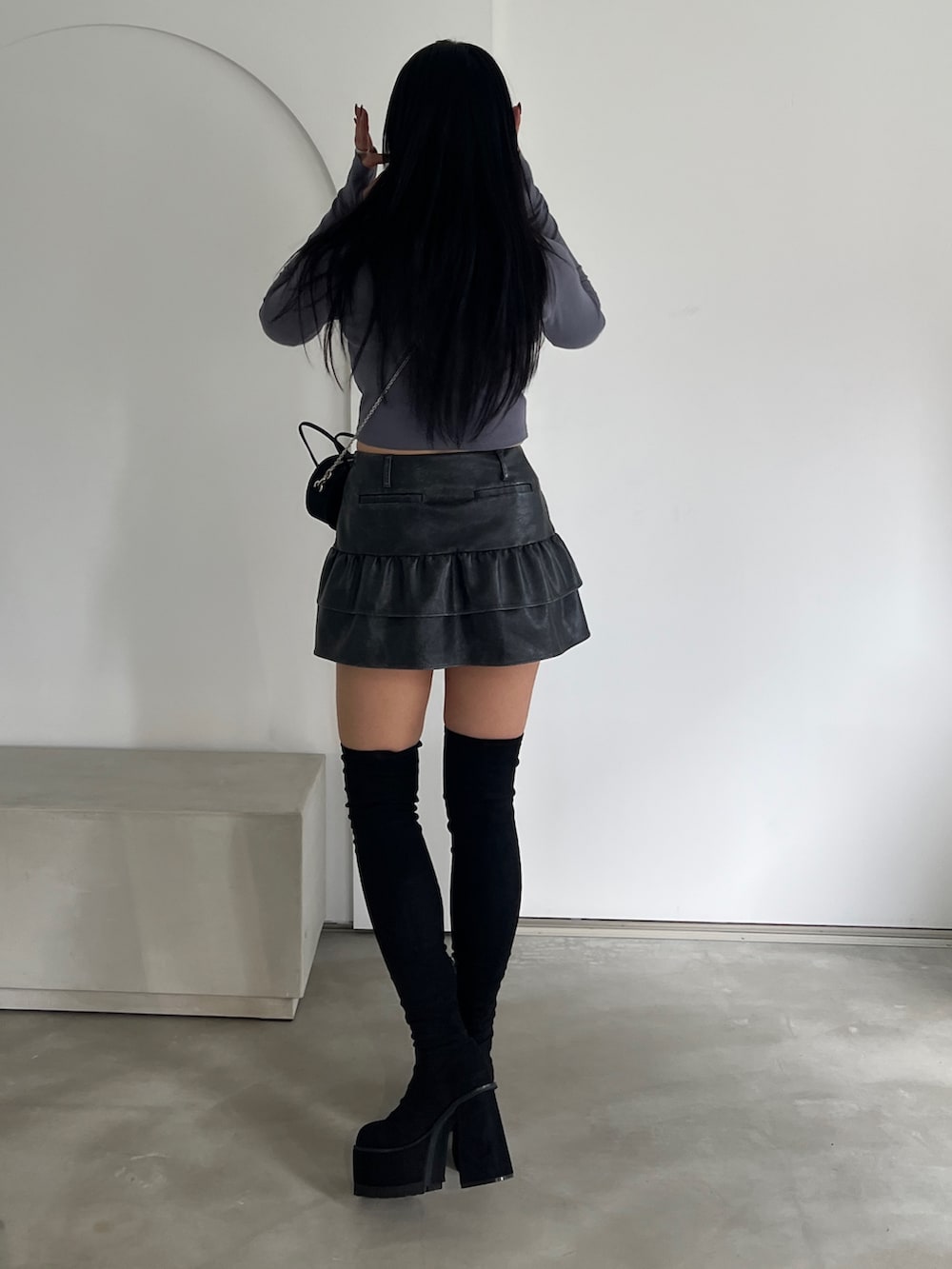 グレー系のTシャツ/カットソー、ブラック系のスカート、ブラック系のブーツを着用したレディースの秋コーディネートの2枚目の写真