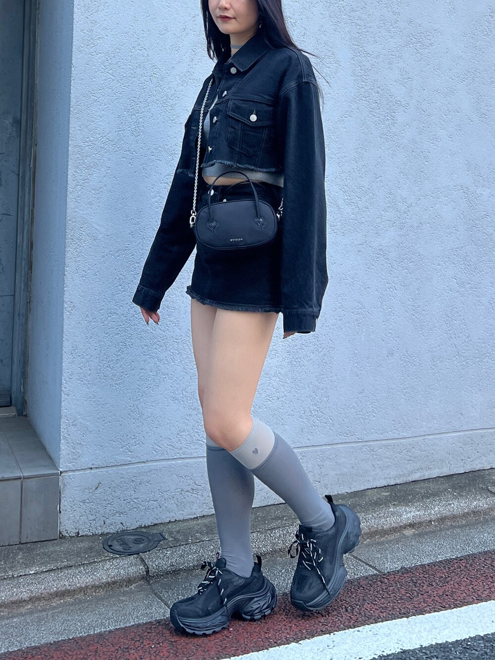 ブラック系のスカート、ブラック系のデニムジャケット、グレー系のニット/セーターを着用したレディースの夏コーディネートの2枚目の写真