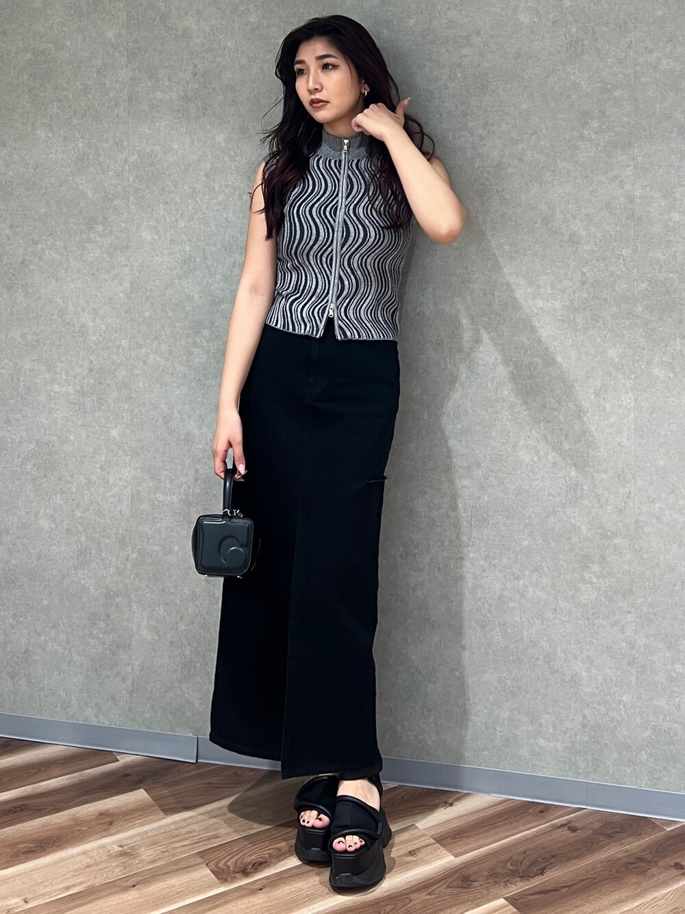 グレー系のタンクトップ、ブラック系のデニムスカート、ブラック系のハンドバッグを着用したレディースの夏コーディネートの2枚目の写真