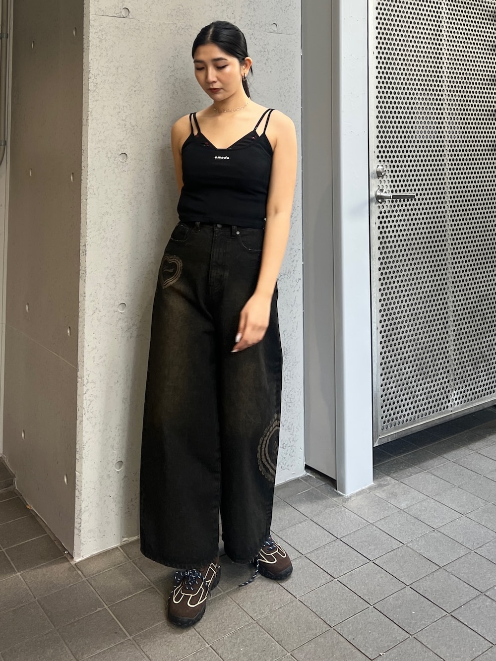 ブラック系のキャミソール、ブラック系のデニムパンツ、ブラウン系のスニーカーを着用したレディースの春コーディネートの3枚目の写真